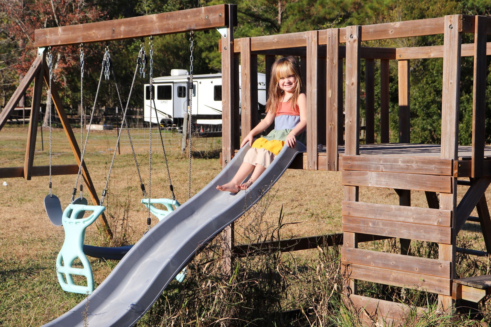A little girl is sitting on a slide at a playground