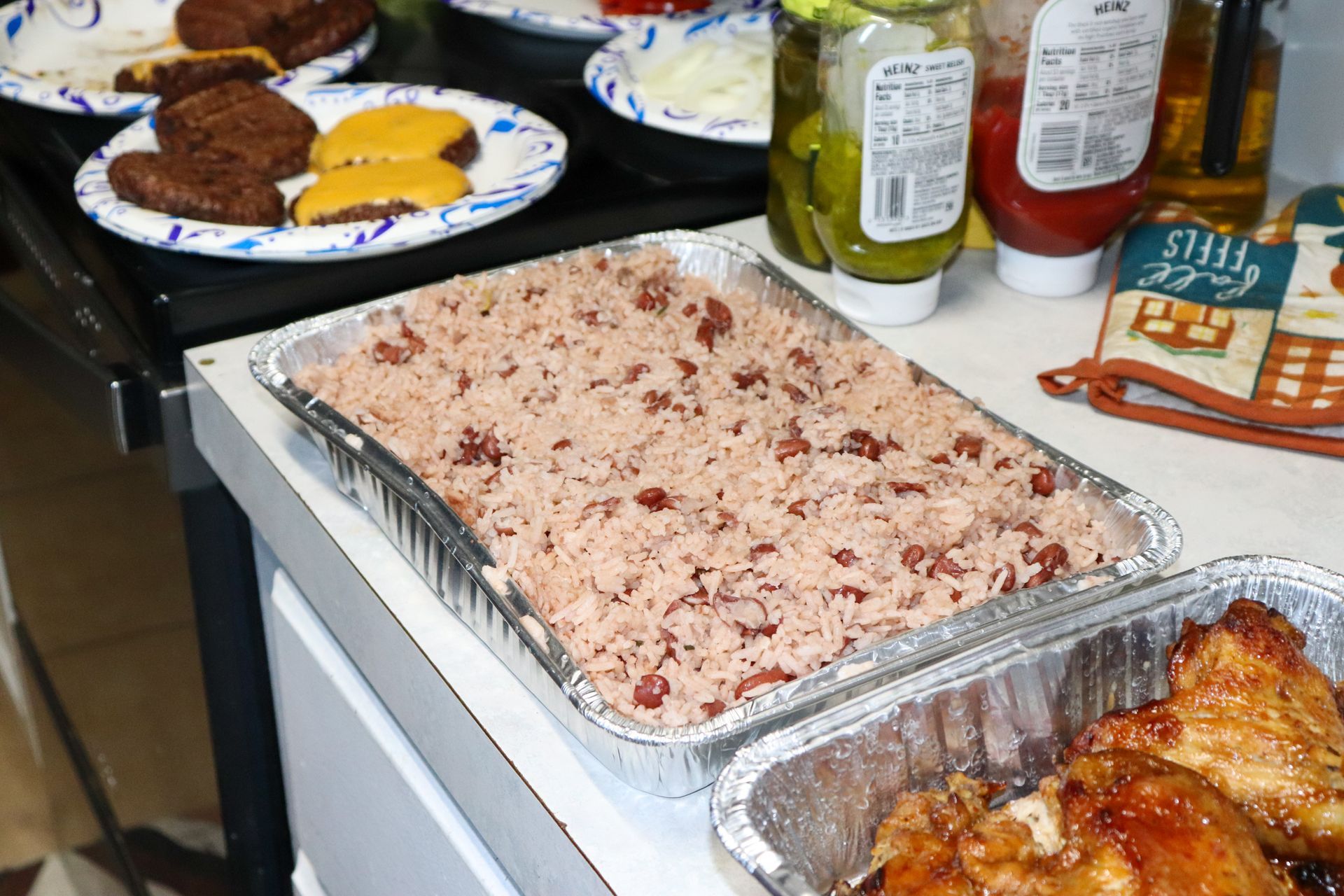 Several trays of food are on a counter including rice and chicken