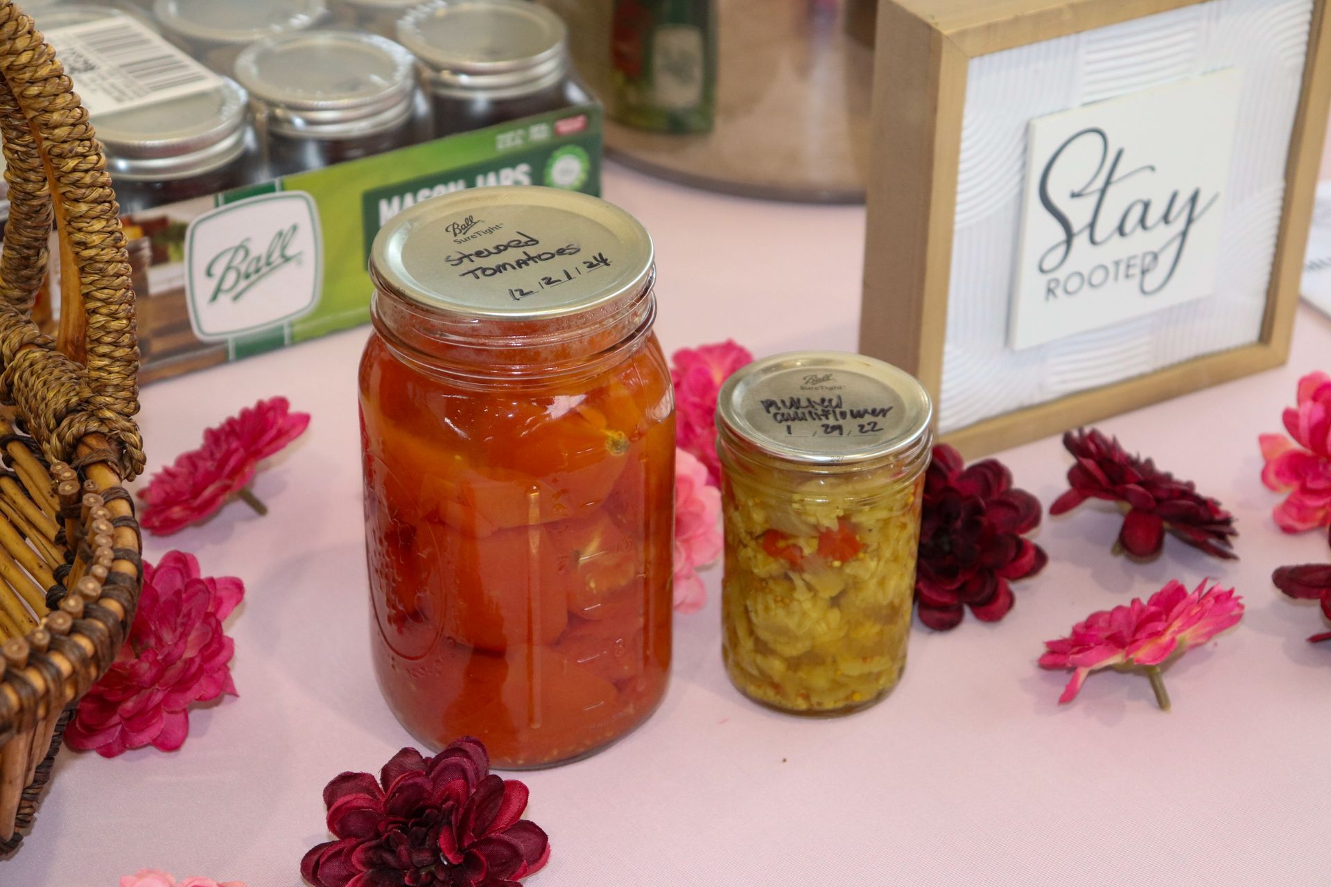 A jar of jam and a jar of pickles are sitting on a table.