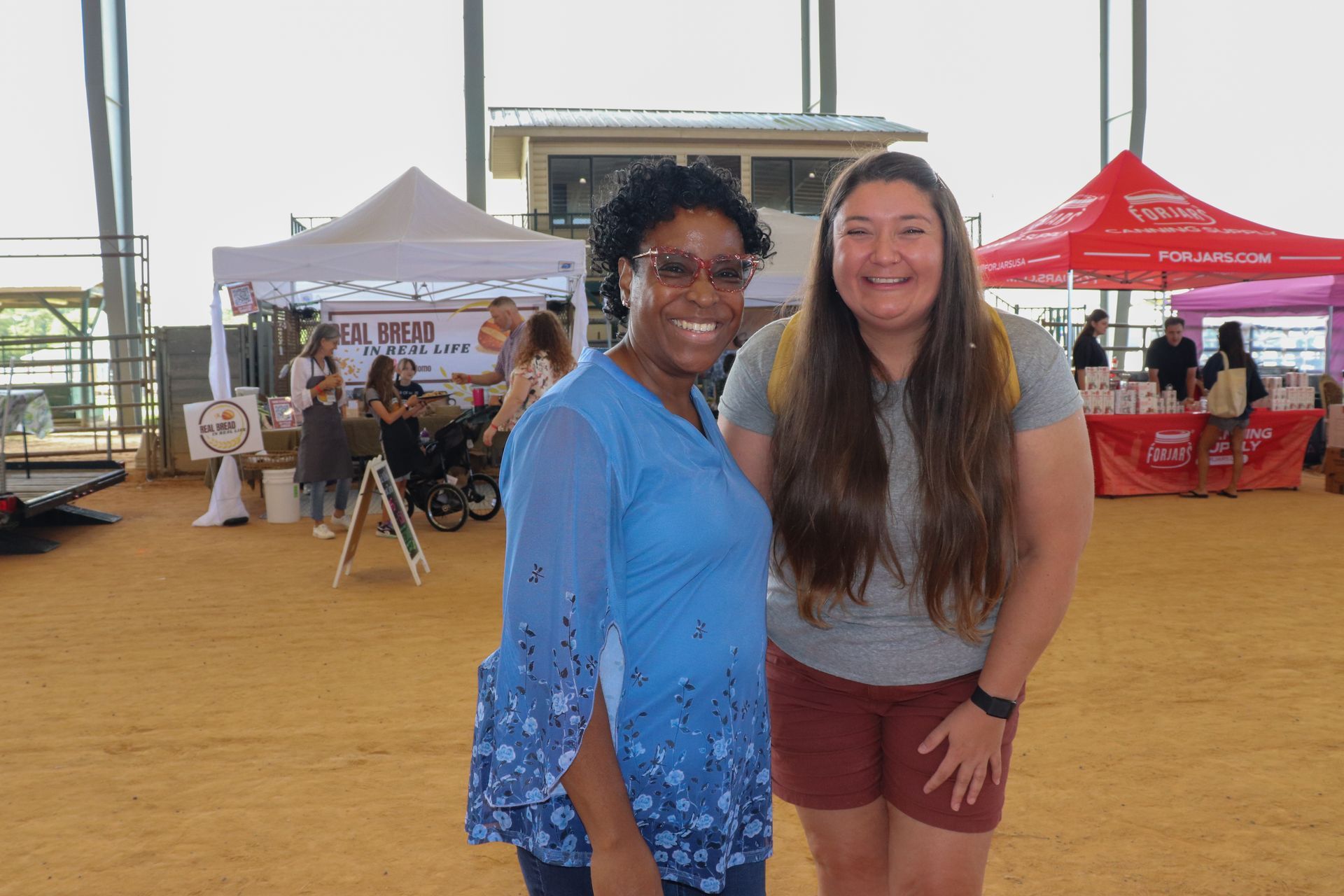 Two women are posing for a picture in front of a tent.