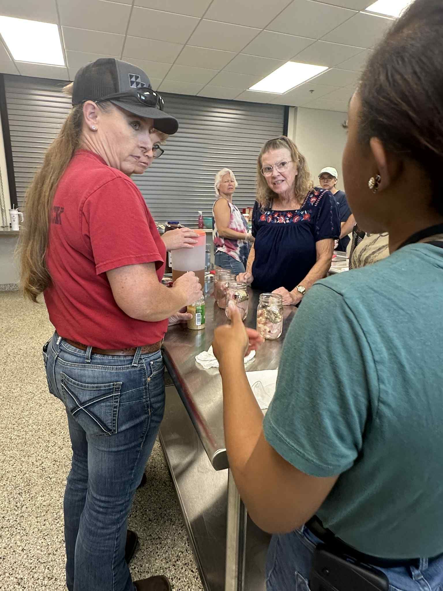 A group of women are standing around a counter in a kitchen.