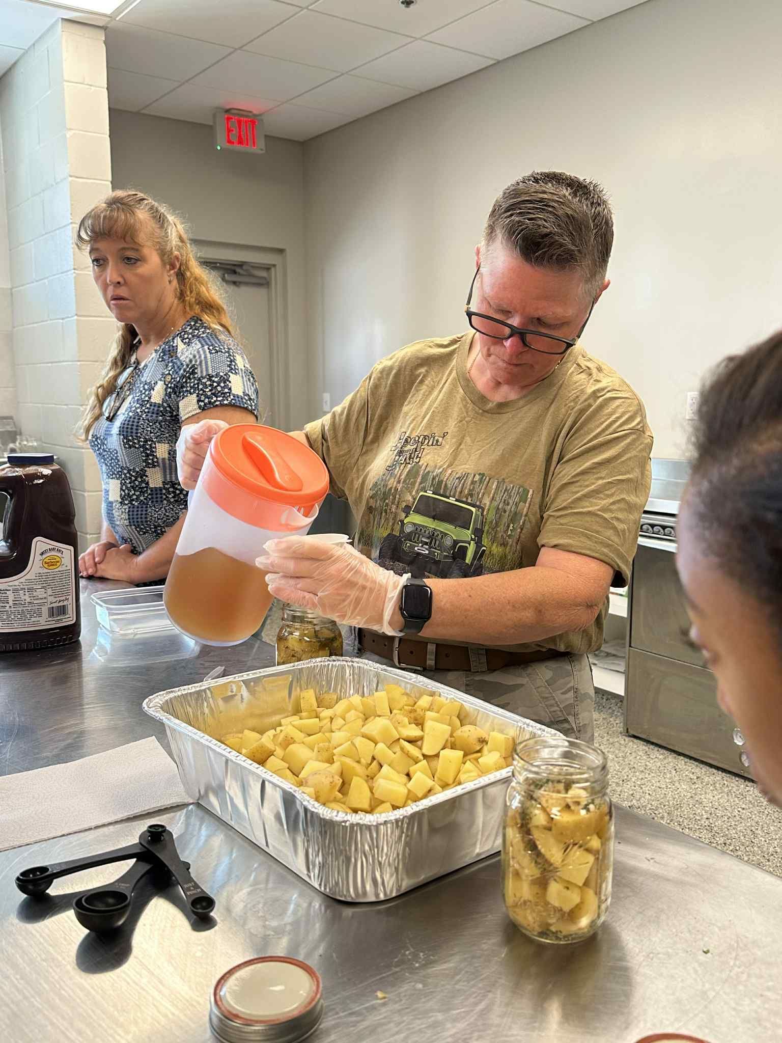 A man is pouring liquid into a pan of food.