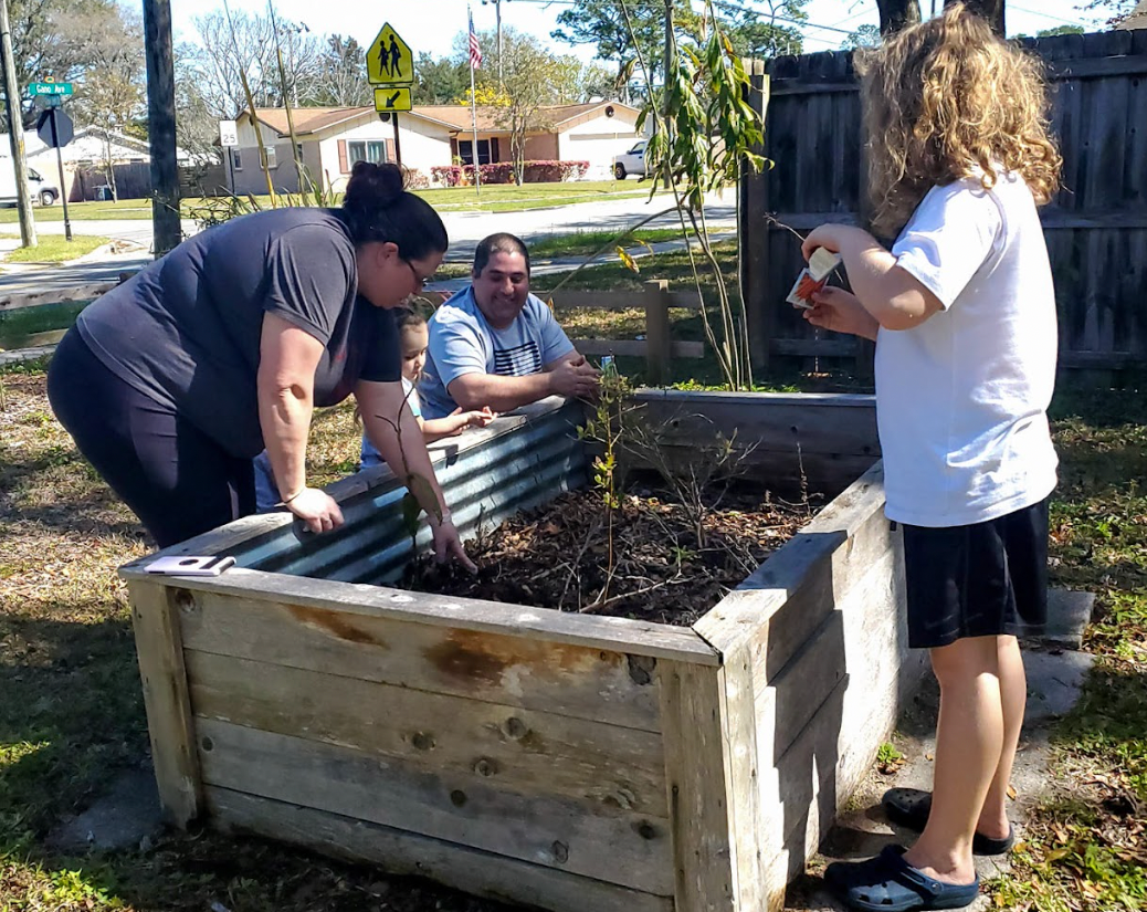 A group of people are standing around a wooden planter.