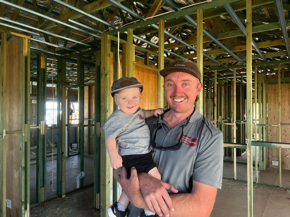 Man Is Holding A Baby In A Building Under Construction — Builder In Gympie, QLD