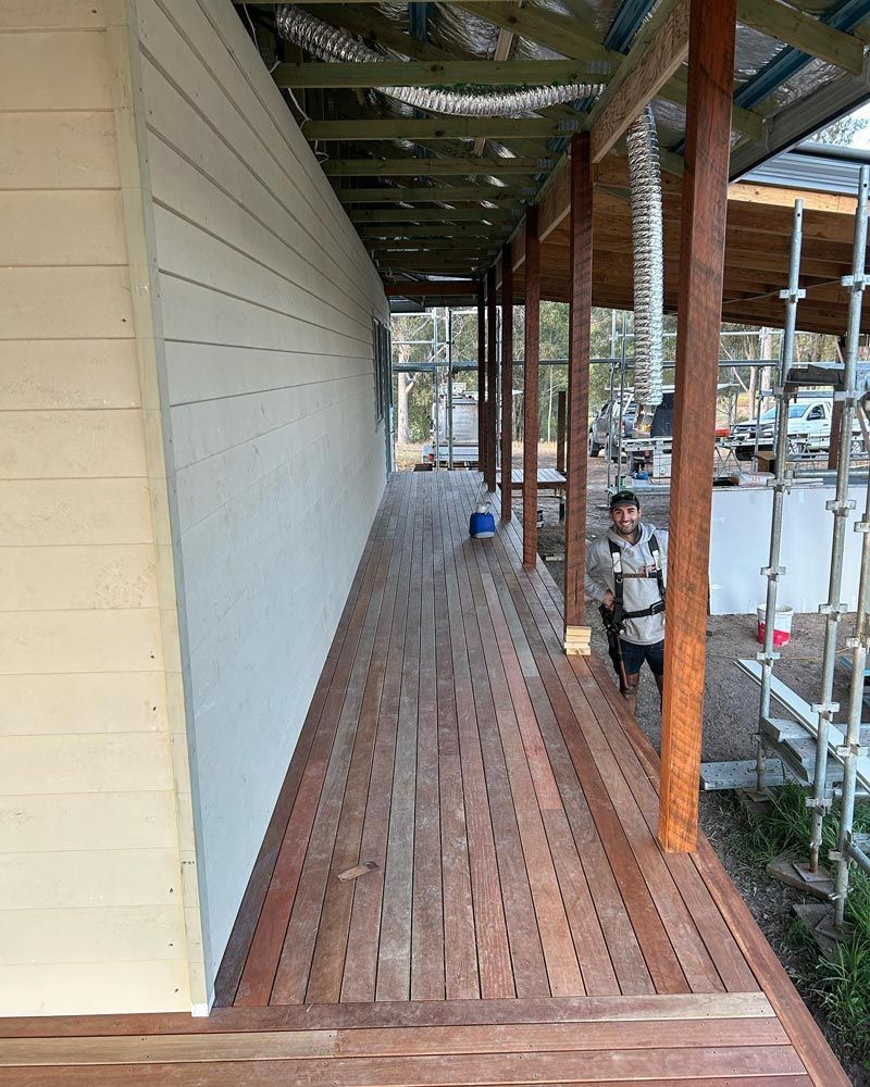 Man Is Standing On A Wooden Deck Next To A Building — Builder In Gympie, QLD