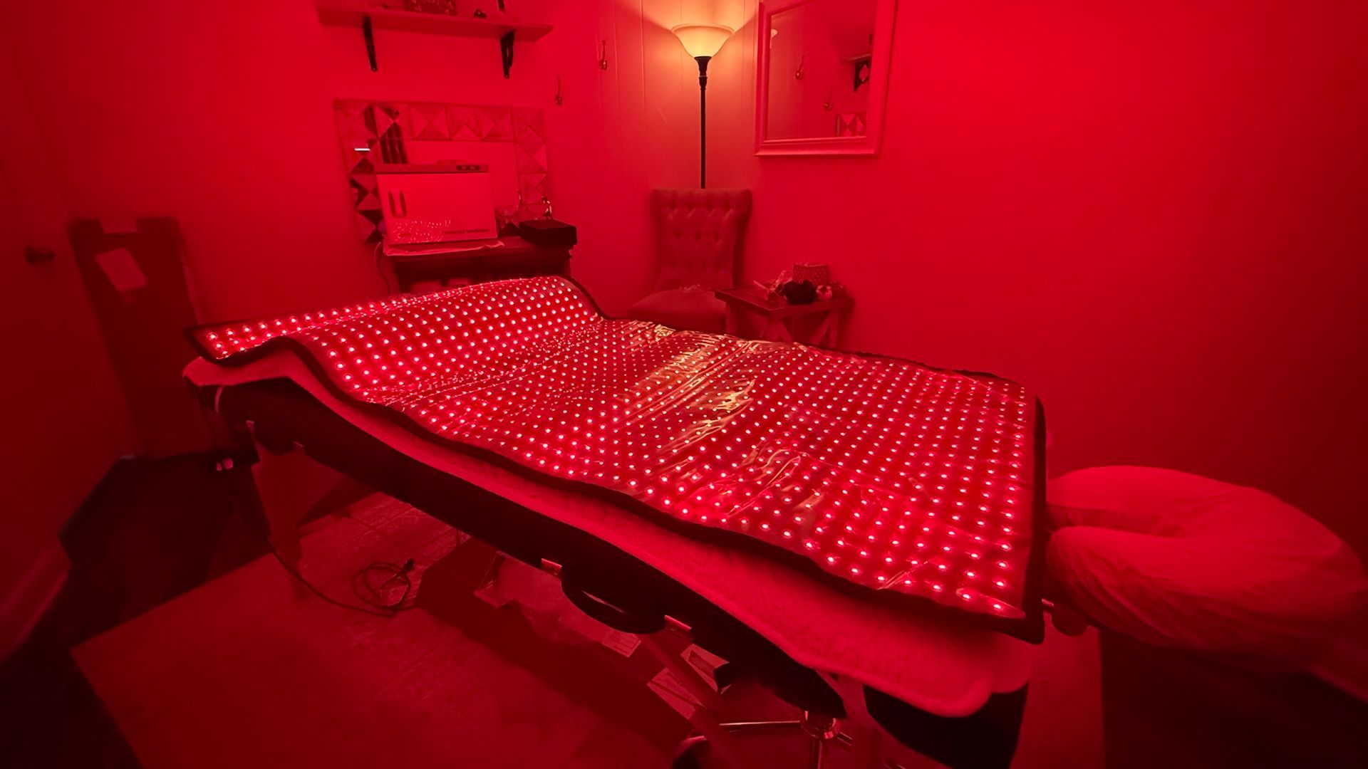 Red light therapy bed in a dimly lit room.
