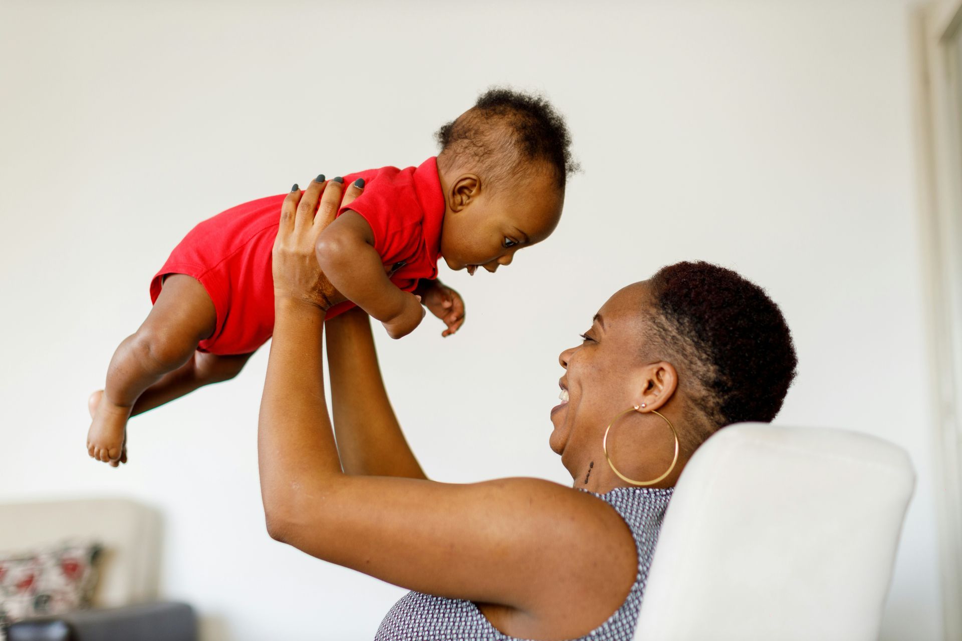 A woman is holding a baby up in the air.