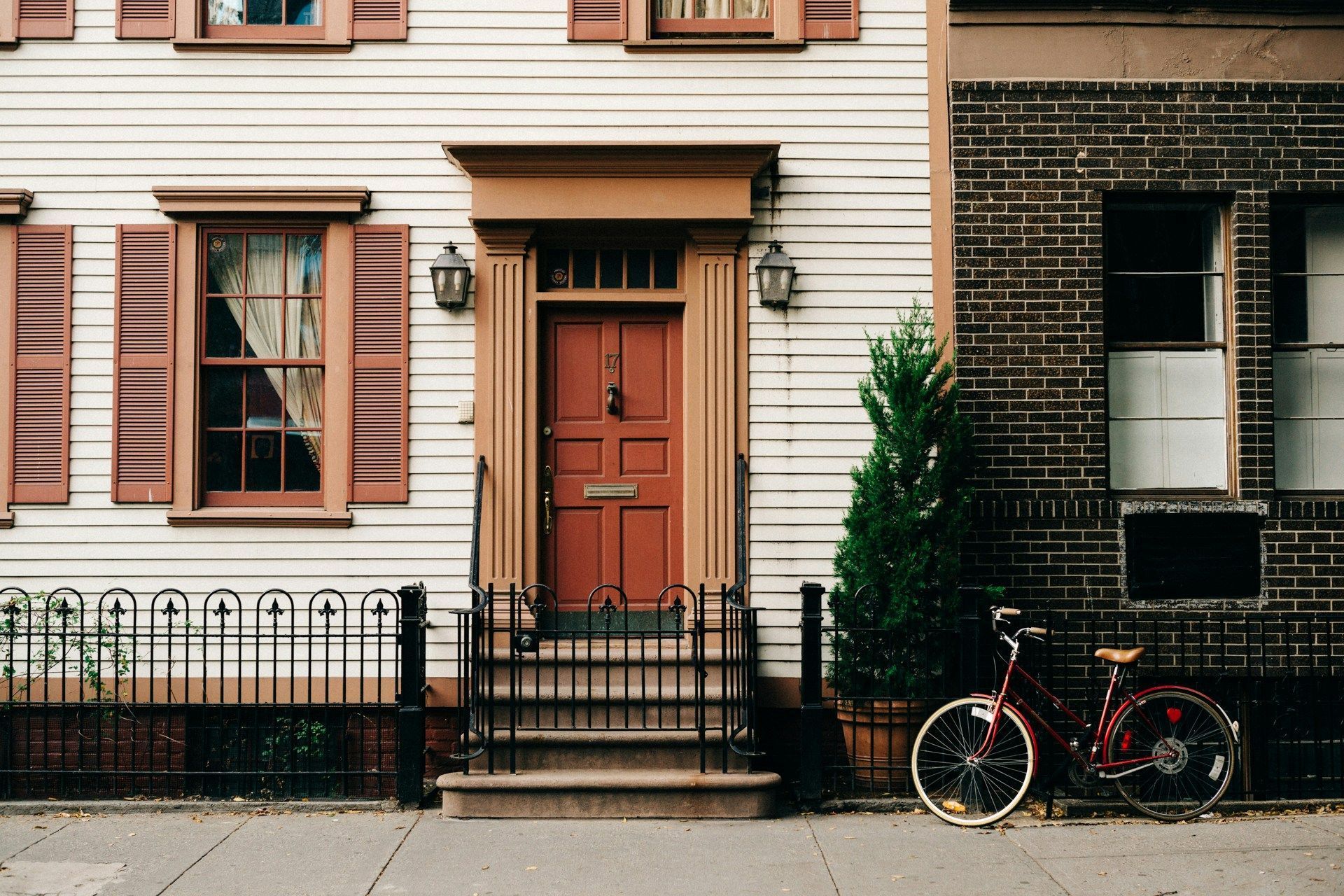 A bicycle is parked in front of a house with a red door