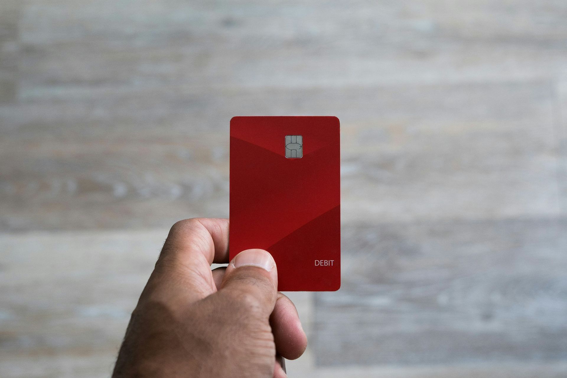 A person is holding a red credit card in their hand.