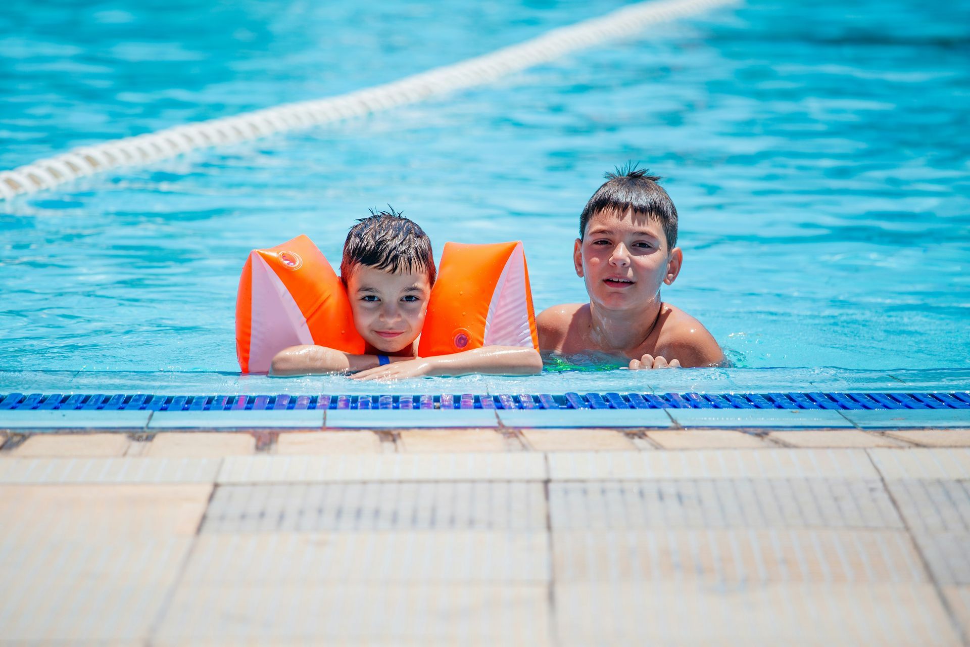 Two young boys are swimming in a swimming pool.