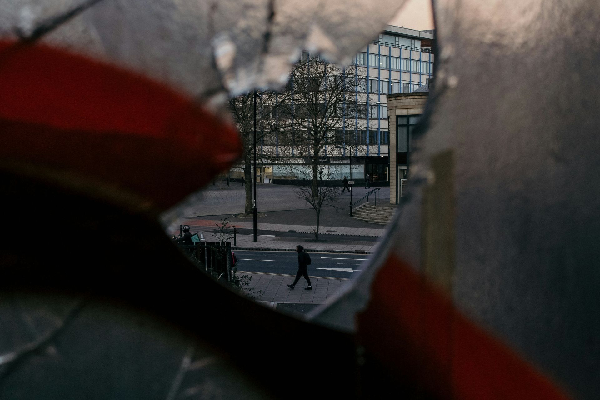 A reflection of a person walking down a street in a broken mirror