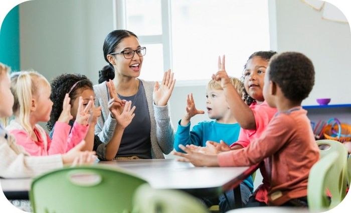 Teacher sitting at table with kids, teaching them how to count.