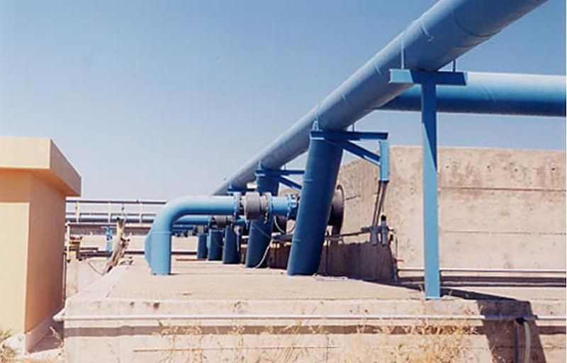 Tubi blu su supporti contro una struttura in cemento, sotto un cielo limpido.