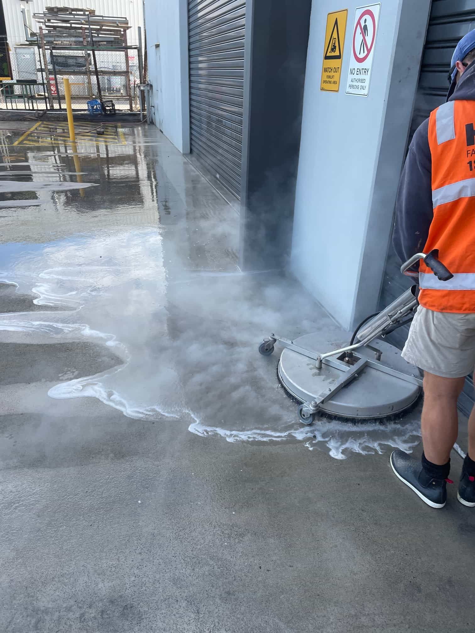 A man is cleaning a concrete floor with a machine. — Hard Surface Cleaners in Clayton, VIC