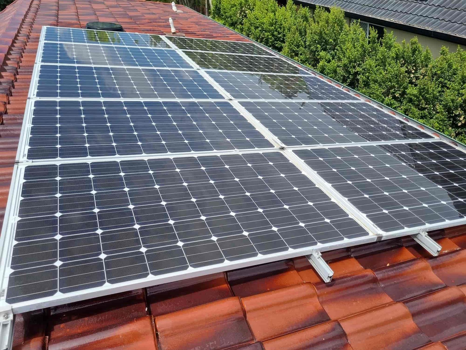A row of solar panels are sitting on top of a tiled roof. — Hard Surface Cleaners in Clayton, VIC
