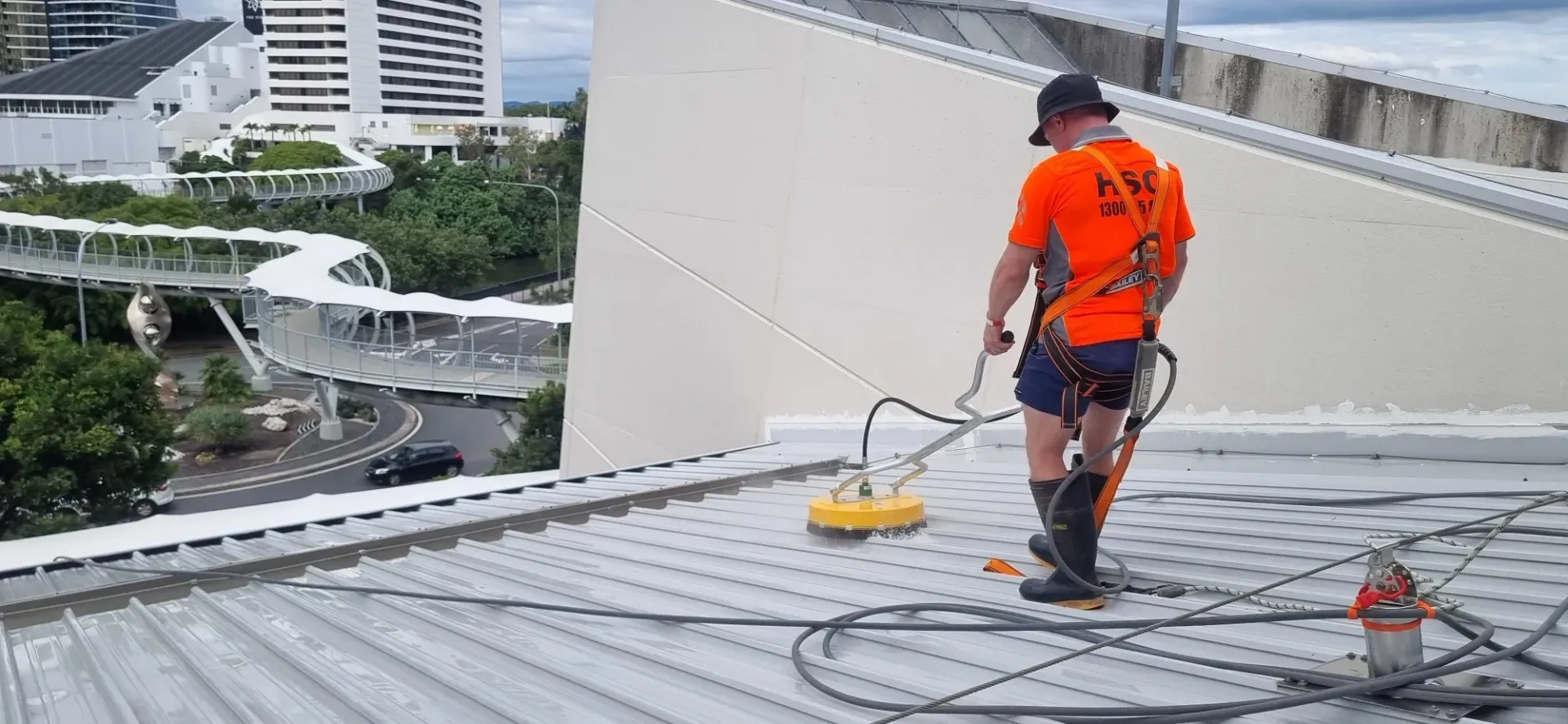 A man is cleaning the roof of a building with a machine. — Hard Surface Cleaners in Gold Coast, QLD