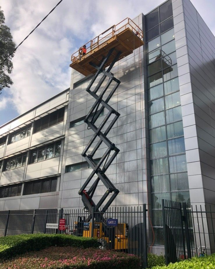 A man on a cherry picker cleaning windows