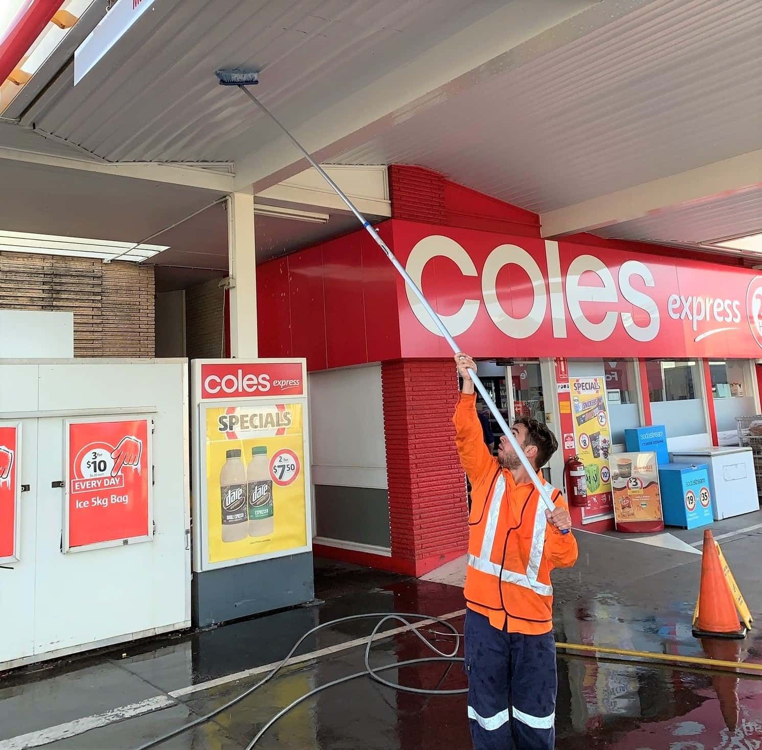 A man is cleaning the ceiling of a coles store — Hard Surface Cleaners in Clayton, VIC
