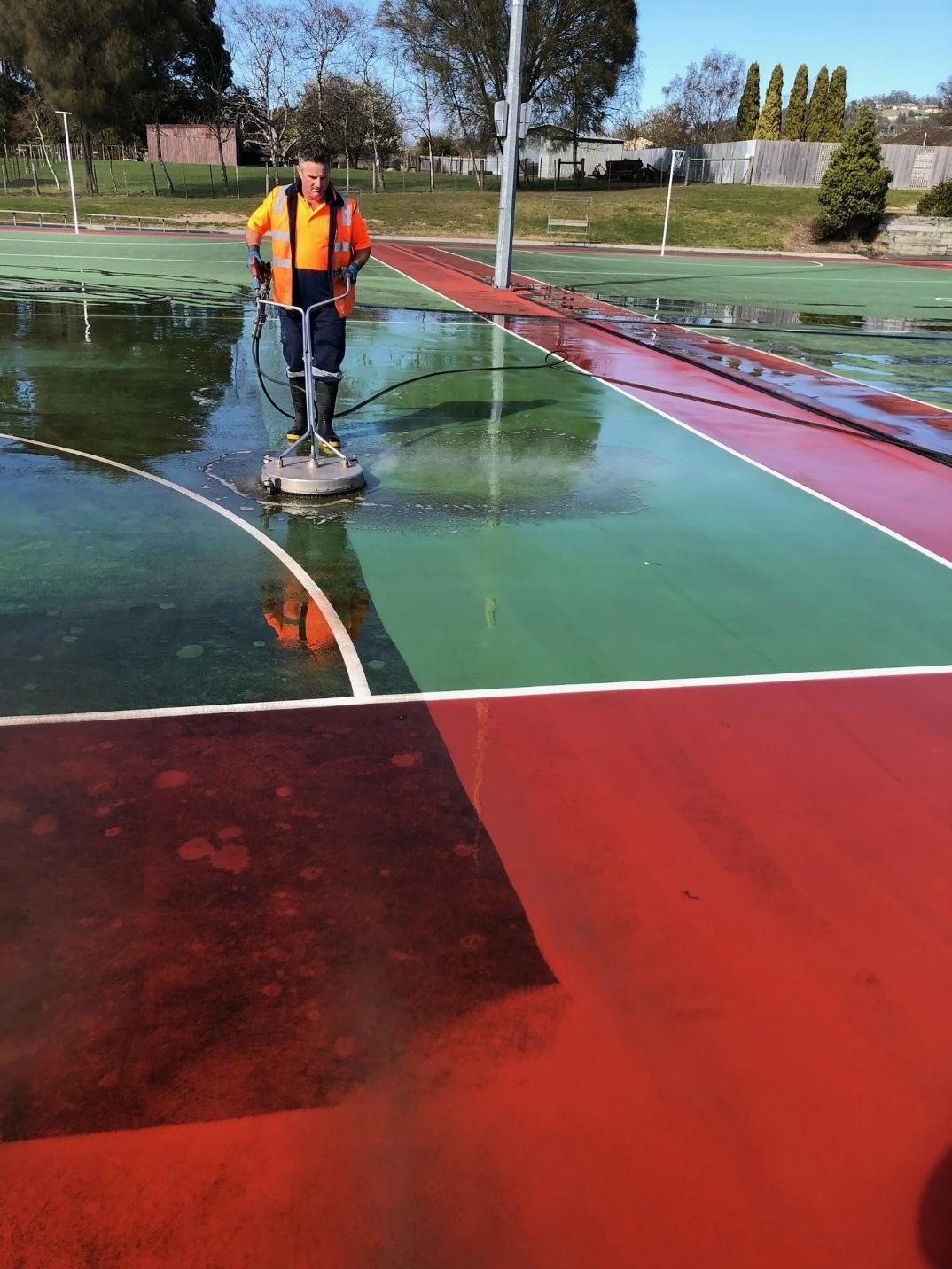 A Man Is Cleaning a Tennis Court with A Machine — Hard Surface Cleaners in Melbourne, VIC