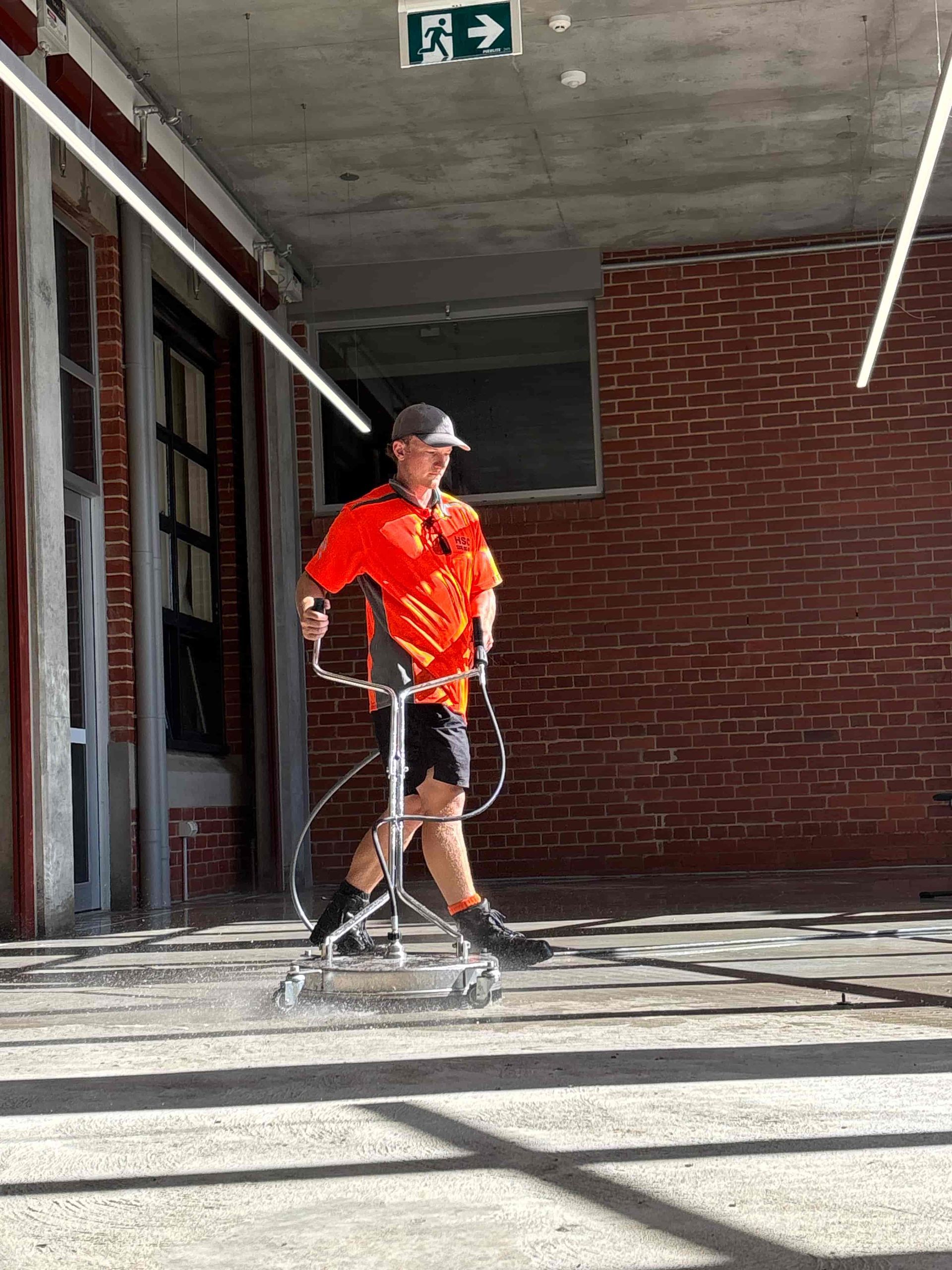 A man is walking with a walker in front of a brick building. — Hard Surface Cleaners in Clayton, VIC