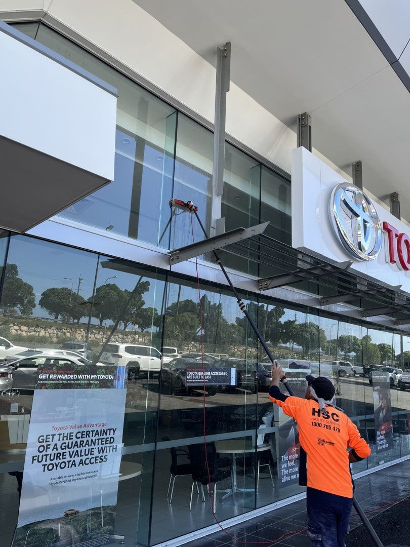 A man is cleaning the windows of a toyota car dealership. — Hard Surface Cleaners in Gold Coast, QLD