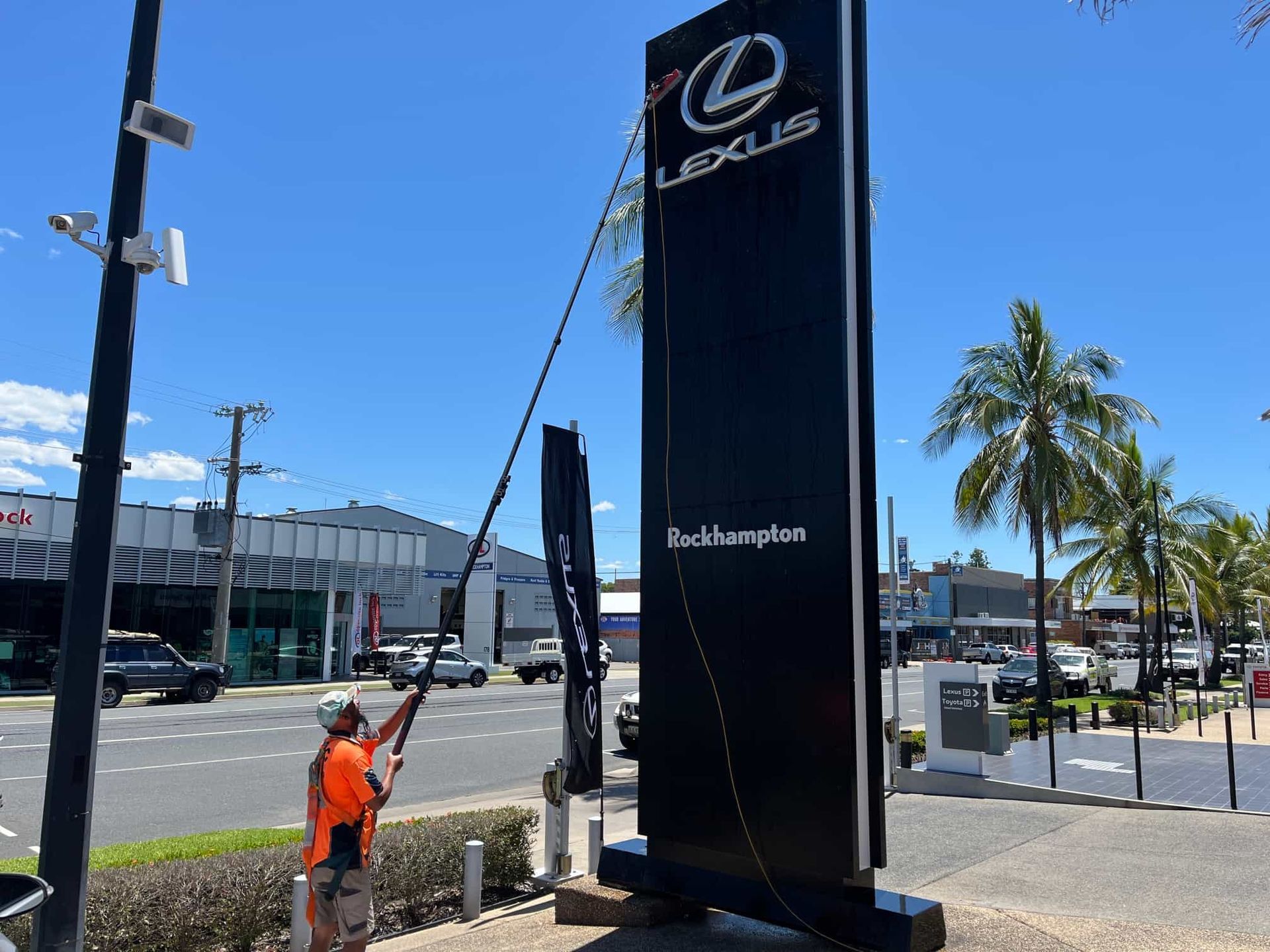 A man is cleaning a large sign that says lexus — Hard Surface Cleaners in Clayton, VIC