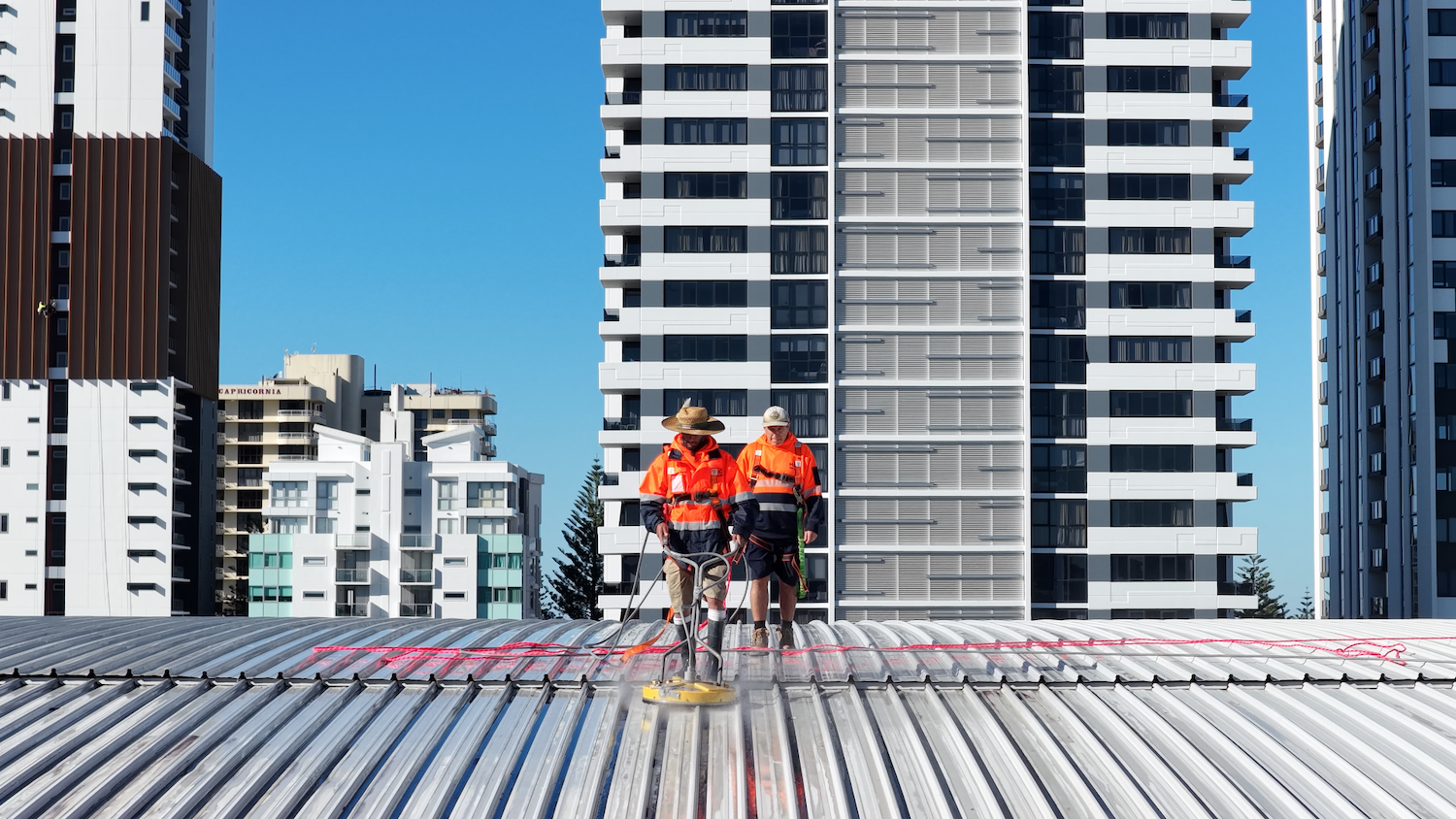 A young boy is cleaning a stone building with a hose. — Hard Surface Cleaners in Clayton, VIC