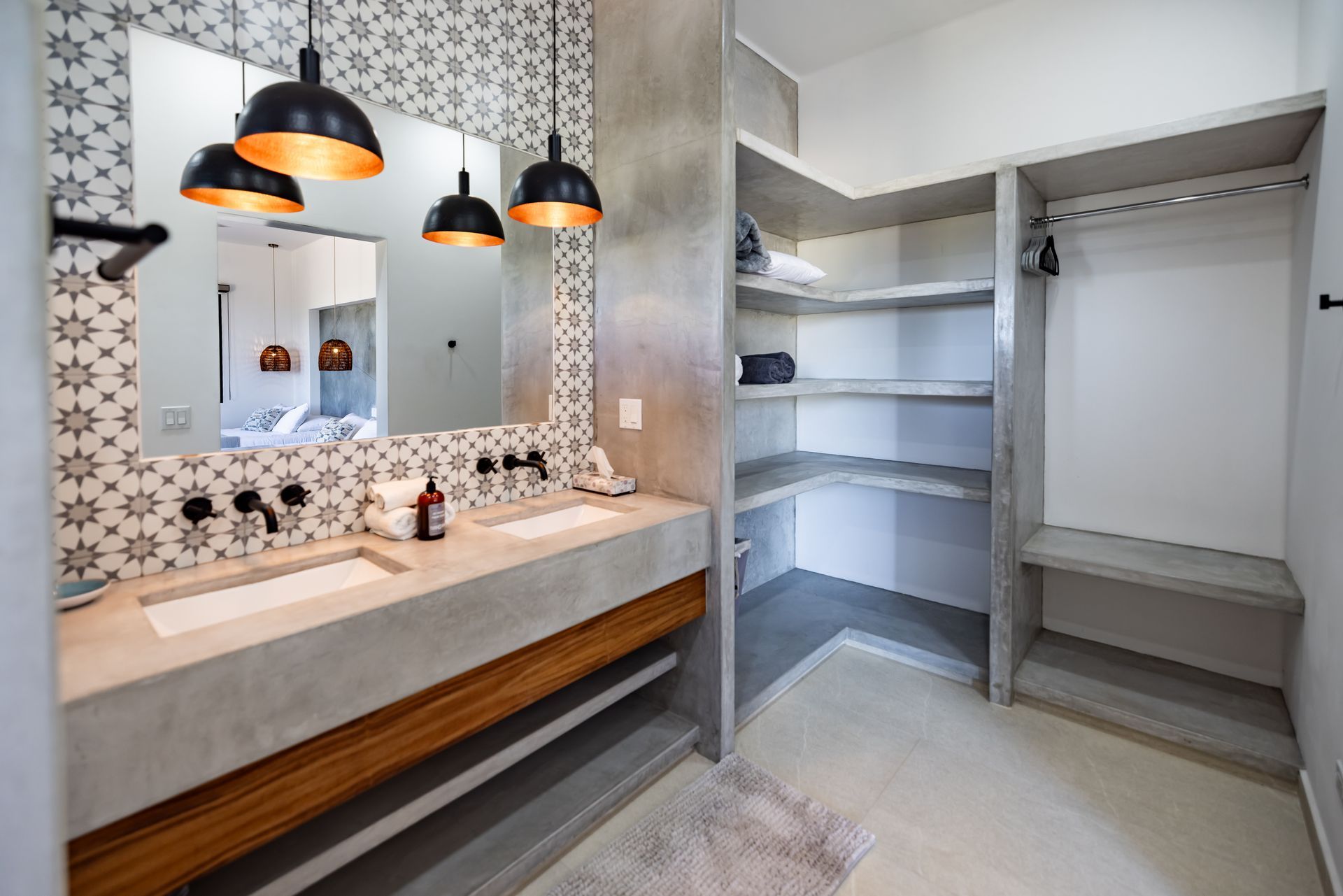 Bathroom with double sinks, patterned backsplash, open shelving, and pendant lights.