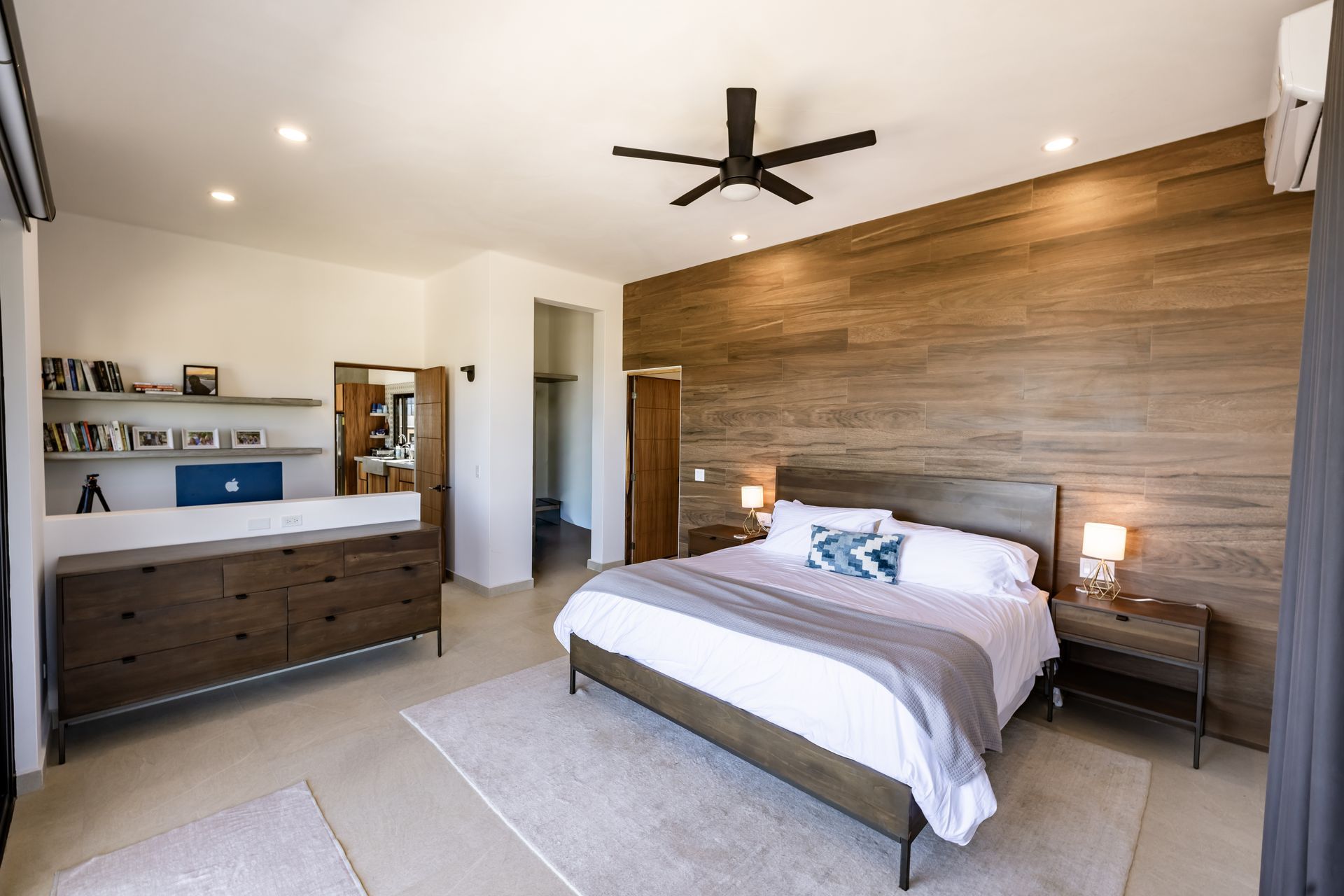 Spacious modern bedroom with wood accent wall, king bed, and neutral tones.