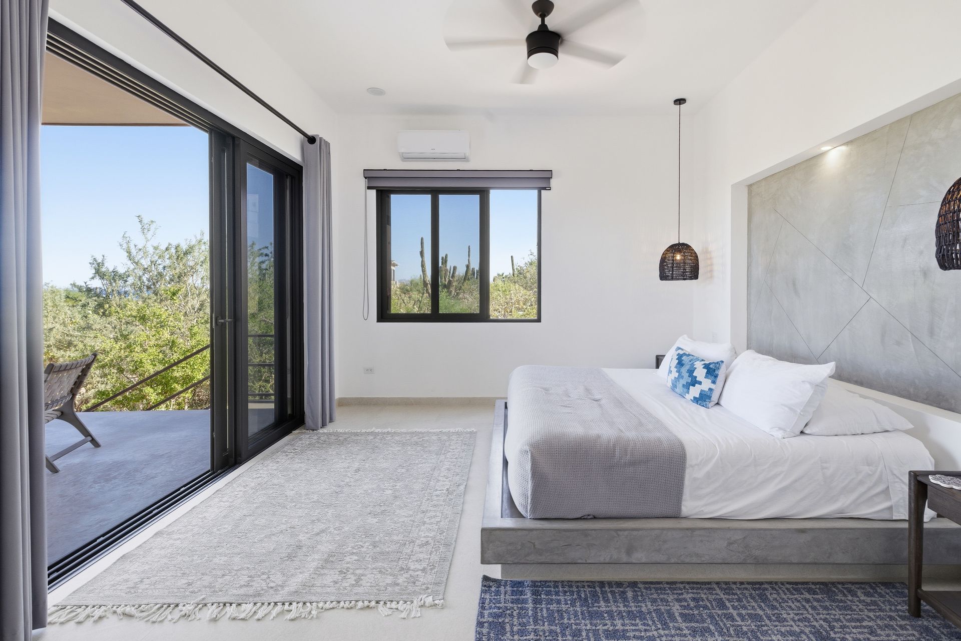 Bedroom with king-size bed, sliding glass door to a balcony, a window, and a ceiling fan.