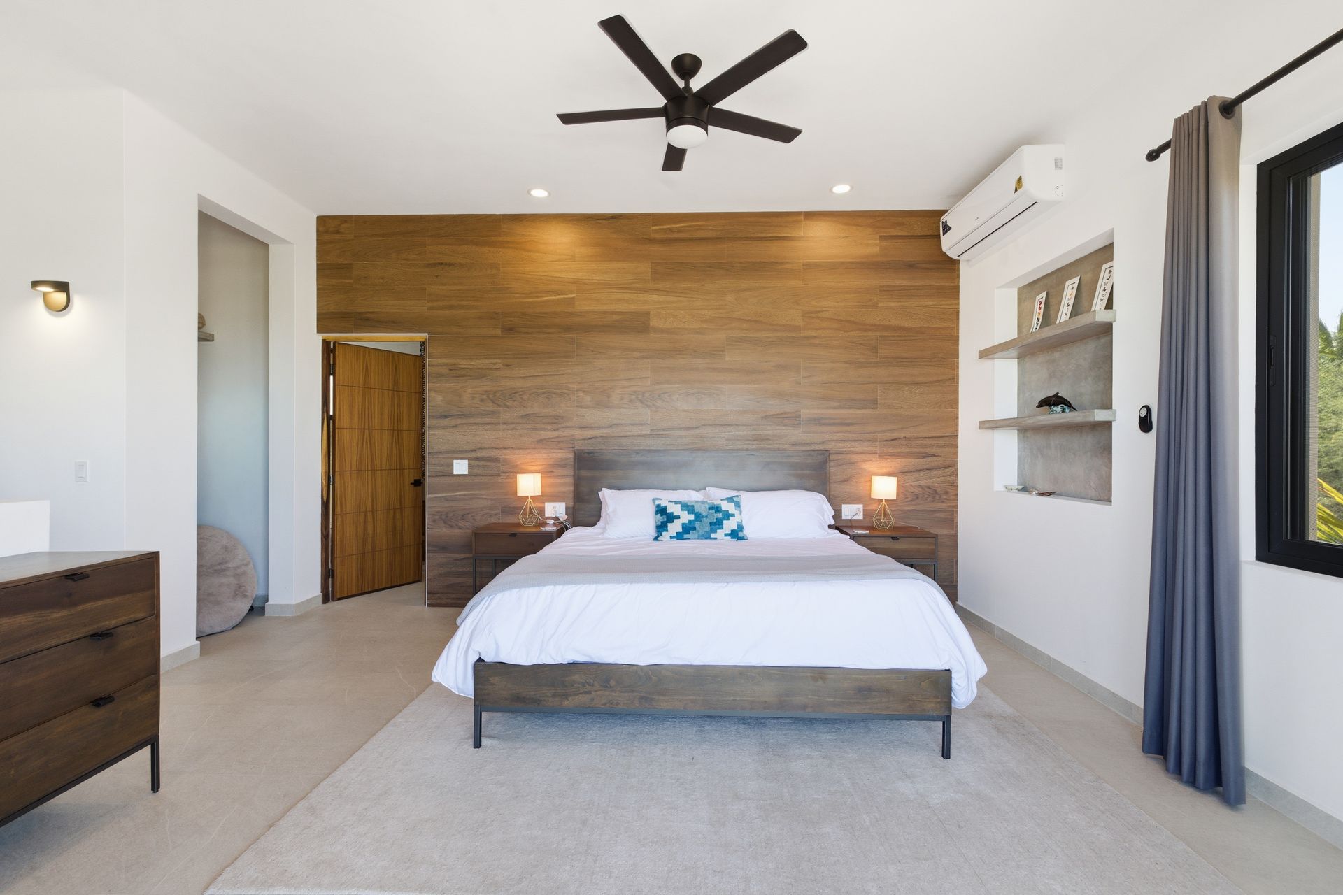 Bedroom with wood accent wall, king bed, ceiling fan, neutral tones.