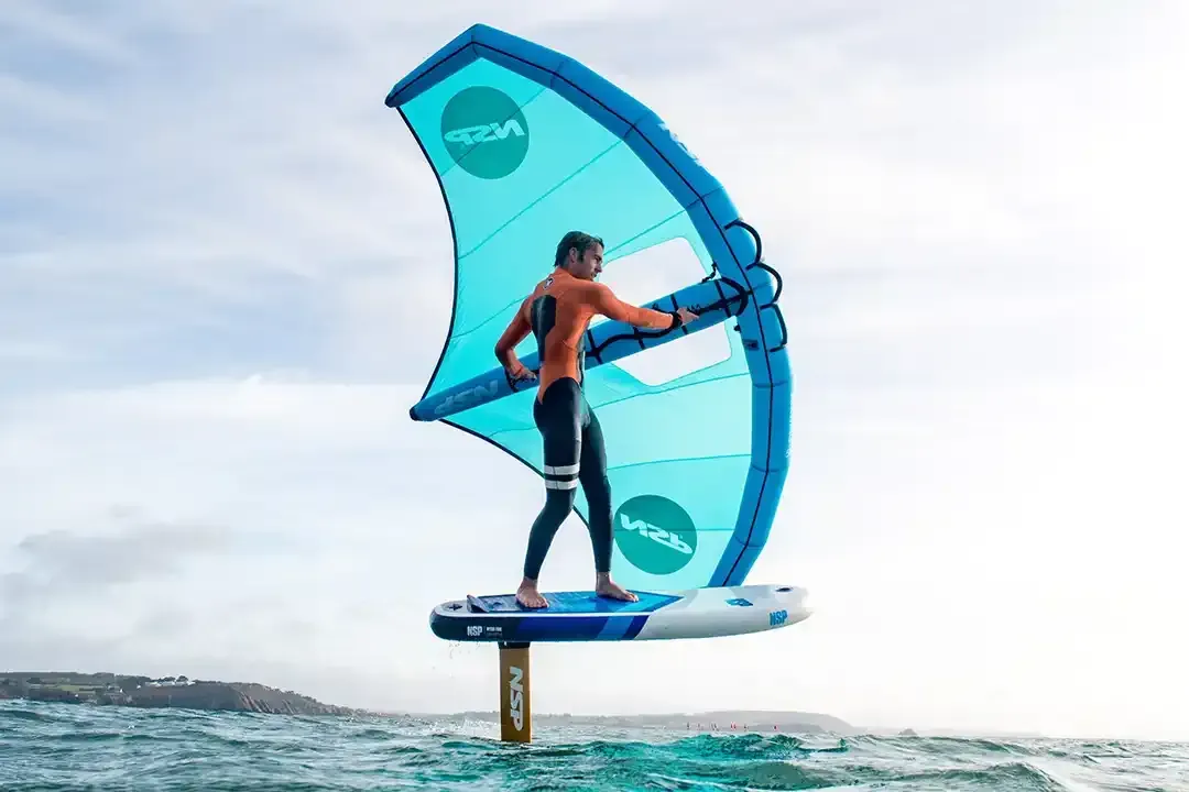 Person wing foiling on a blue and white board with a blue wing over water.