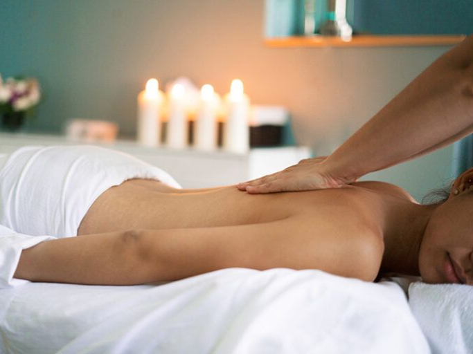 Scuba diver swimming underwater, exhaling bubbles; bright blue water, coral reef.