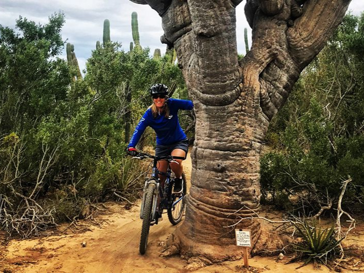 Man paddleboarding on a blue ocean, wearing hat and sunglasses, holding a paddle.