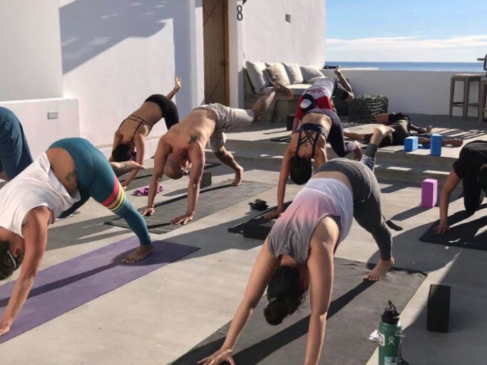 Man paddleboarding on a blue ocean, wearing hat and sunglasses, holding a paddle.