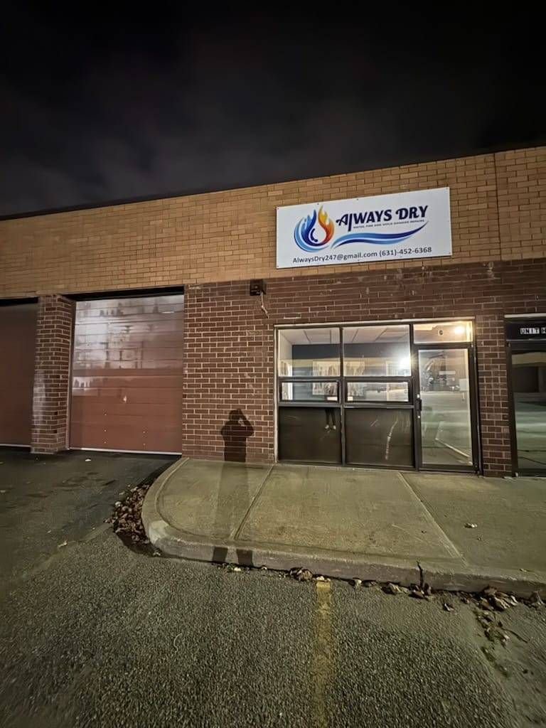 A nighttime view of a brick storefront with a white sign reading 