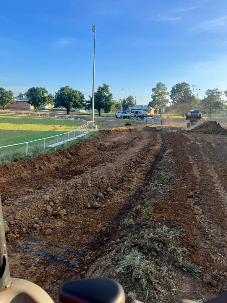 Earthmoving equipment at a construction site with a field in the background on a sunny day.