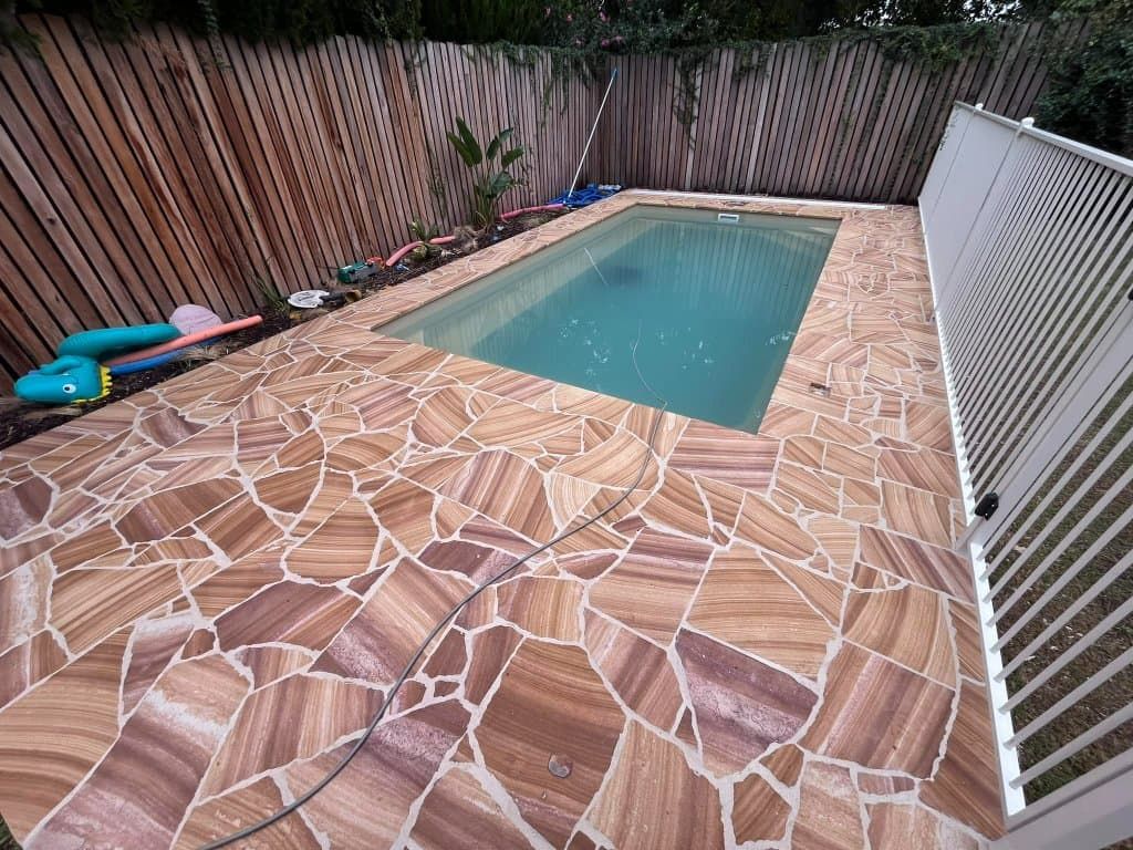 Pool area with sandstone paving and wooden and white fences — Darlington Landscaping in Dubbo, NSW