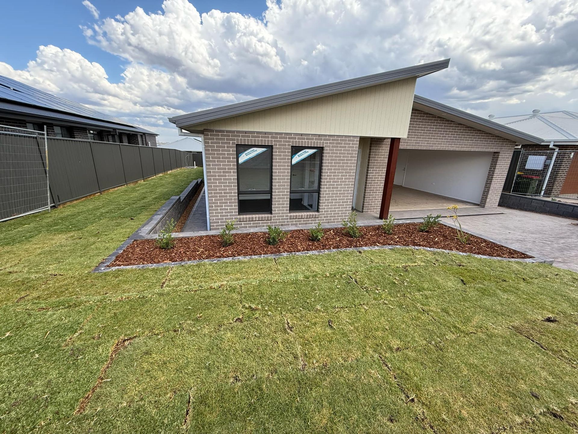 Modern house with a sloping roof, garage, and landscaping on a sunny day — Darlington Landscaping in Dubbo, NSW