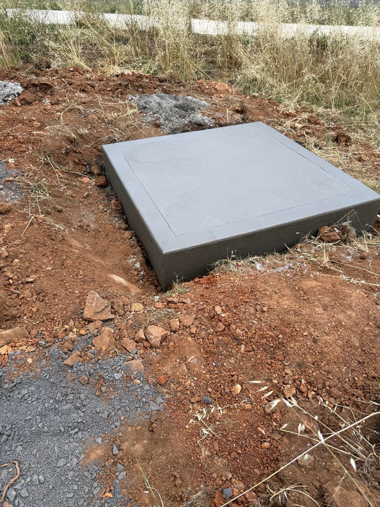 Square concrete slab set into a dug area in dry, reddish-brown earth — Darlington Landscaping in Dubbo, NSW