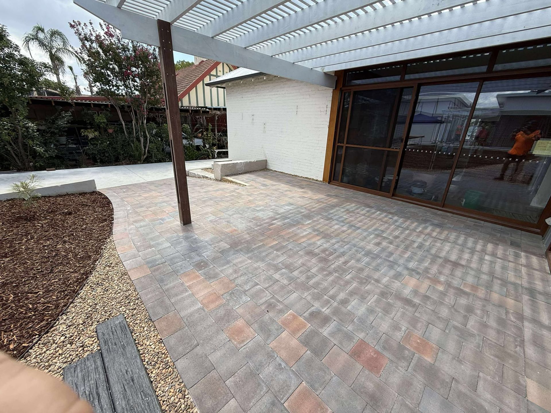Patio with brick pavers, pergola, sliding glass doors, and mulch bed — Darlington Landscaping in Dubbo, NSW