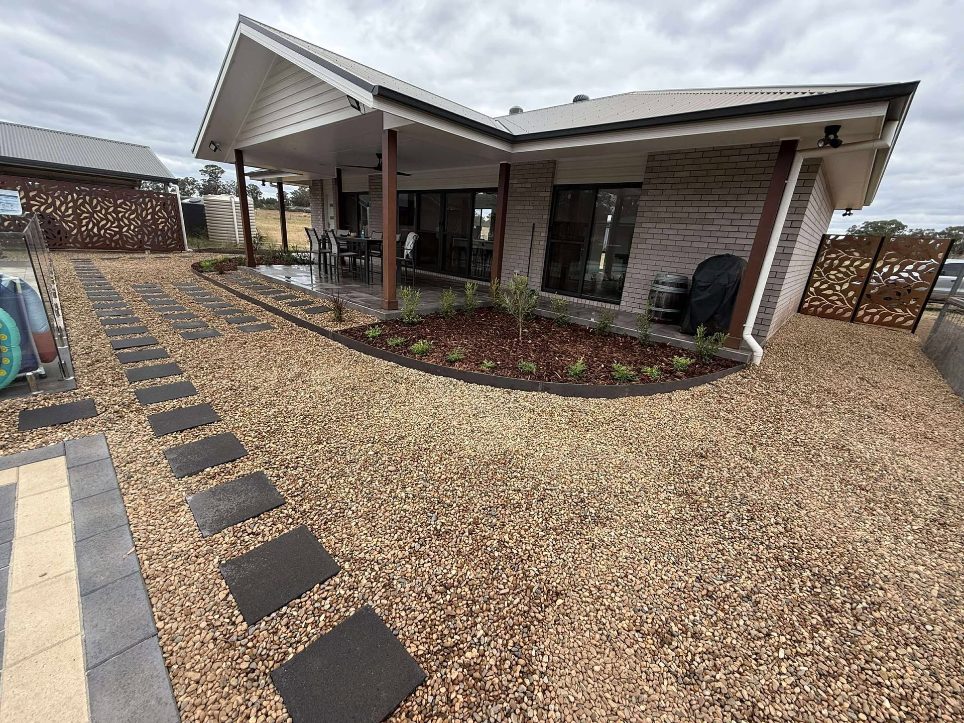 House exterior with gravel yard, stepping stones, brick facade, and covered patio — Darlington Landscaping in Dubbo, NSW