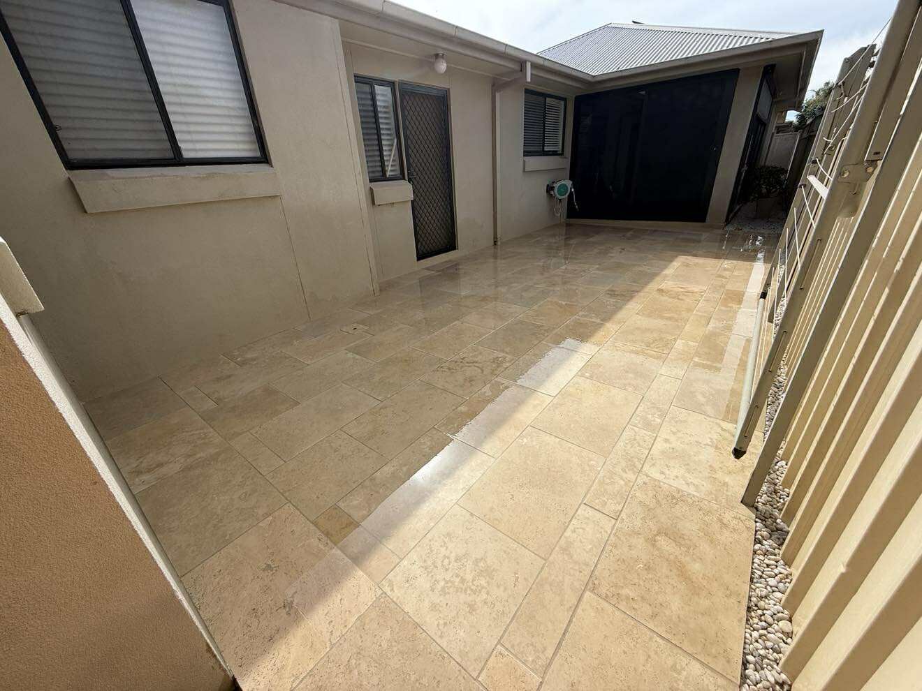 A beige tiled courtyard with a fence and access door — Darlington Landscaping in Dubbo, NSW