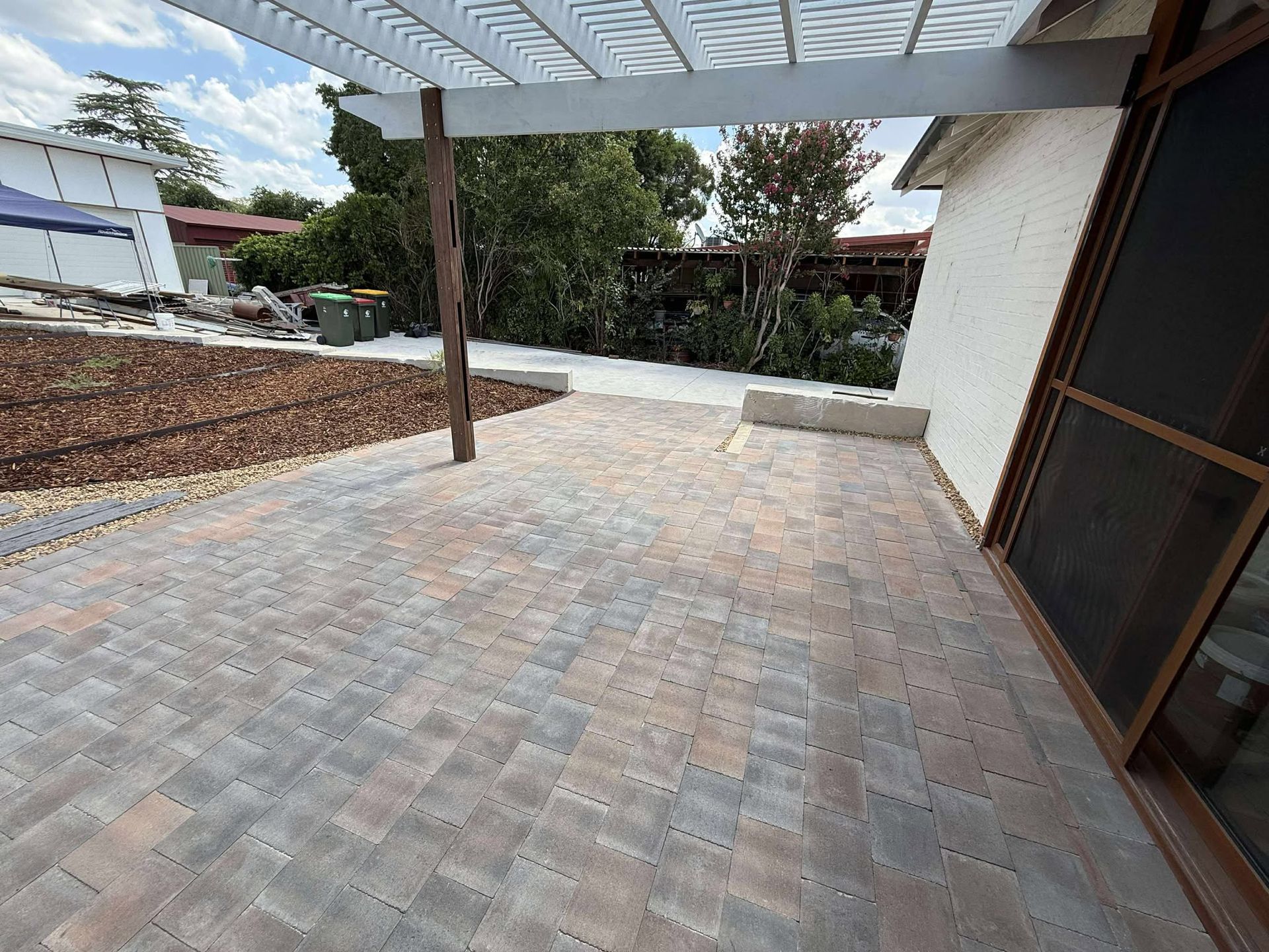 Brick patio under a pergola, leading to a garden — Darlington Landscaping in Dubbo, NSW