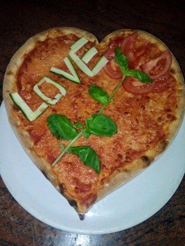 Pizza in forma di cuore con pomodori freschi e la scritta Love