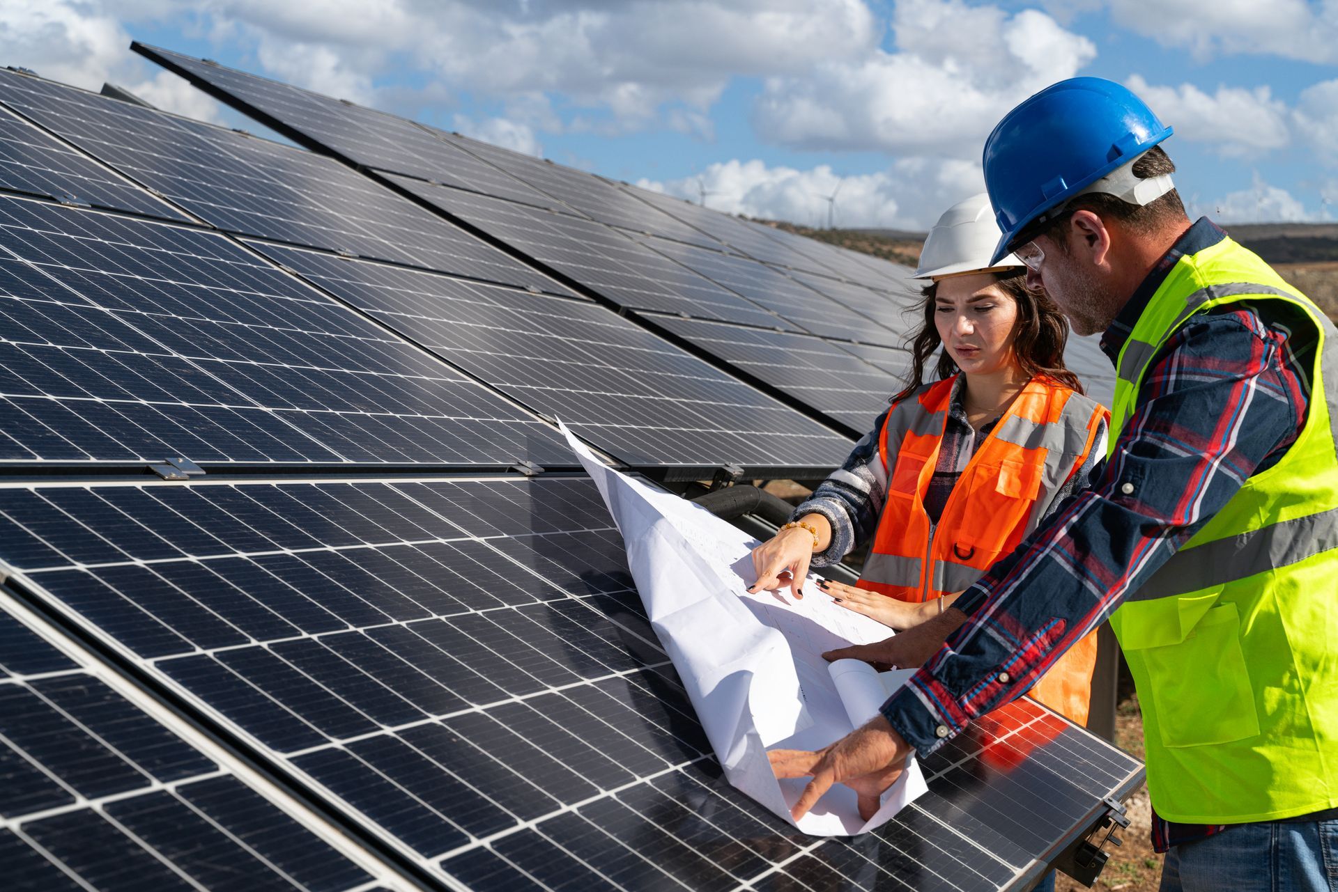 A man and a woman are looking at a blueprint of a solar panel.