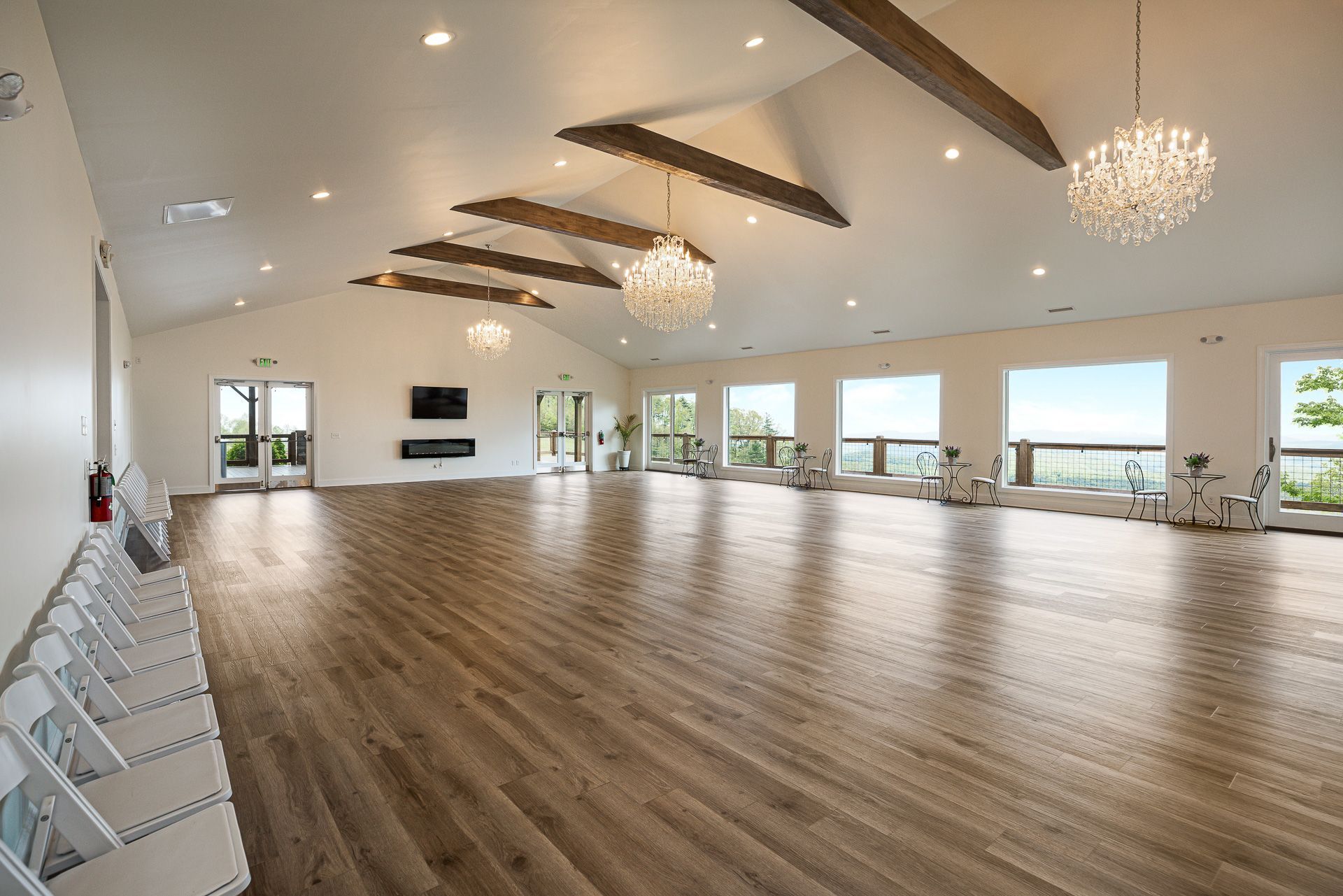 A large empty room with wooden floors and a chandelier hanging from the ceiling.
