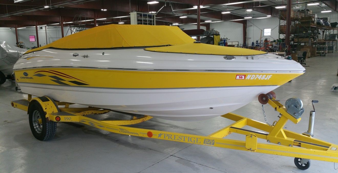 Yellow and white boat on a yellow trailer, covered with a yellow cover, inside a warehouse.