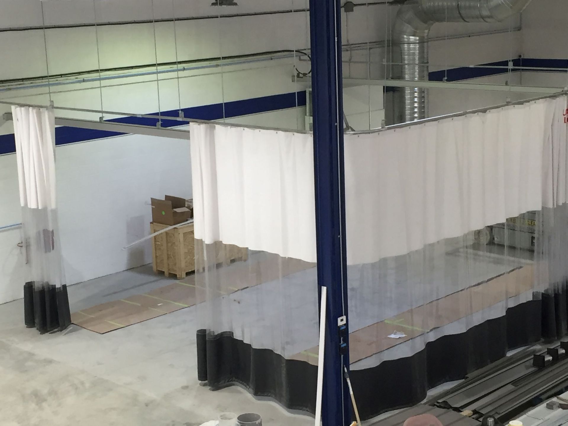 Interior view of a workshop area with white curtains creating enclosed spaces and a blue support column.