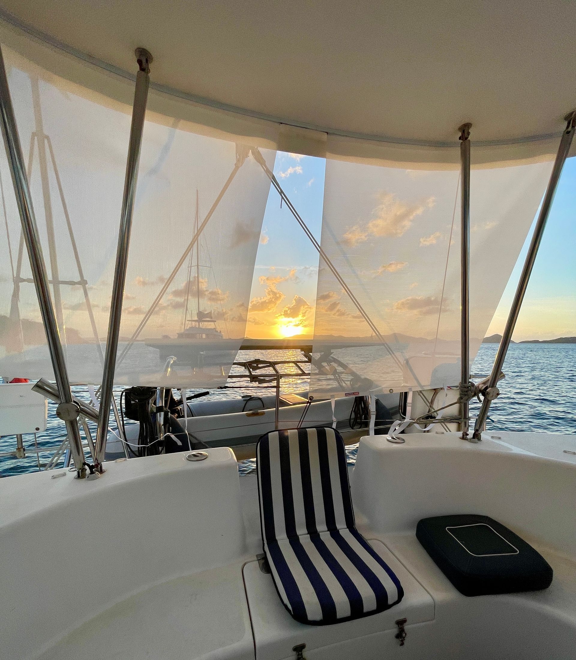 Sunset view from a boat, showing water, sky, and a seat with a striped cushion.